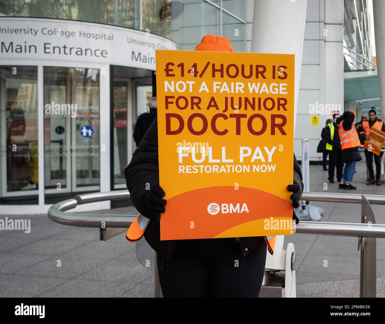 A junior doctor holds up a protest banner outside University College Hospital London, during a doctors strike for a pay increase, April - 2023. Stock Photo