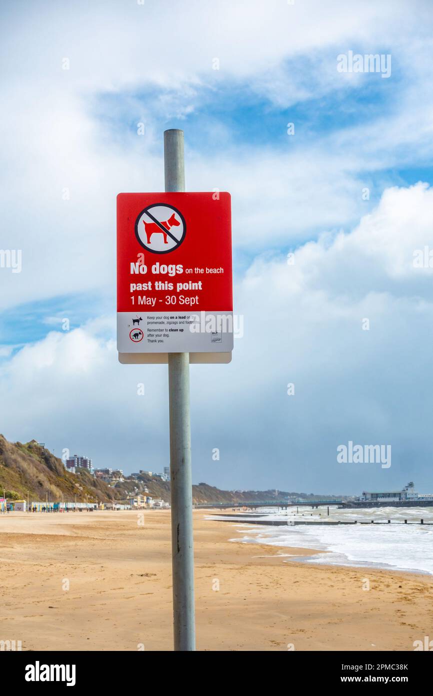 A red sign on Bournemouth Beach in Dorset, UK informing dog owners as