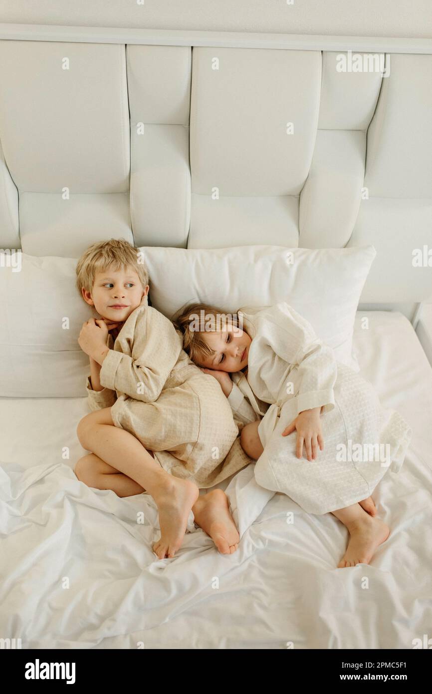 Brother and sister lying on the bed in bathrobes after a shower Stock Photo Alamy
