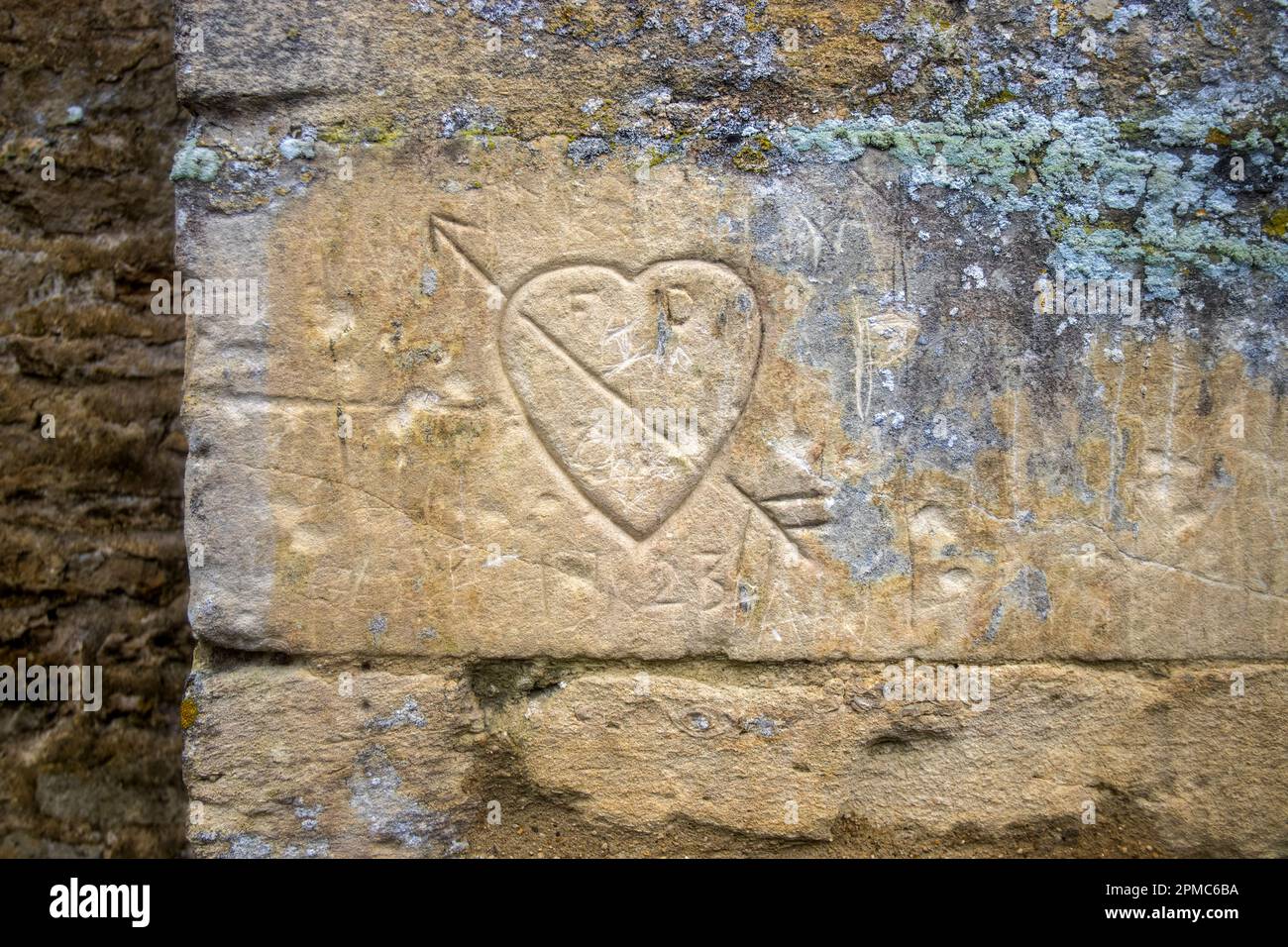 Old graffiti carved into the side of a stone building in Bibury