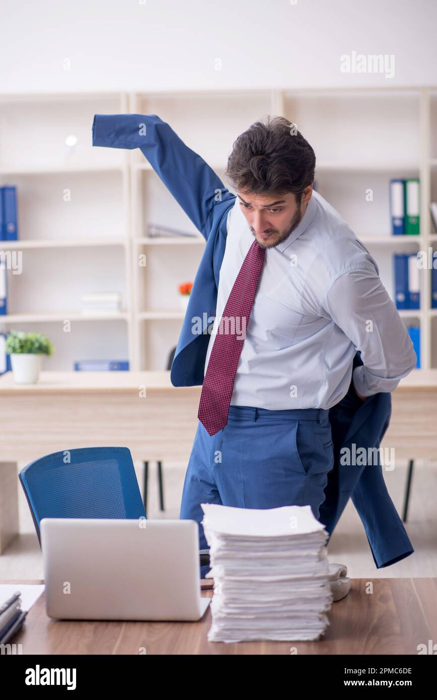 Young employee and too much work at workplace Stock Photo