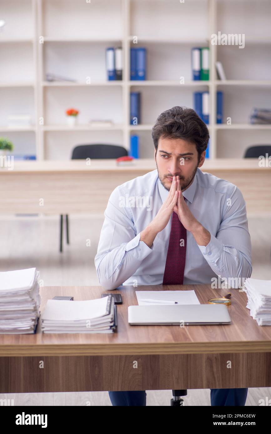 Young employee and too much work at workplace Stock Photo