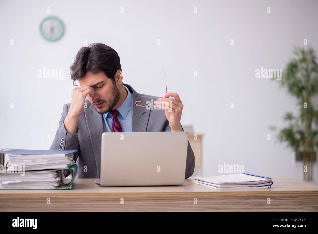 Young employee unhappy with excessive work at workplace Stock Photo