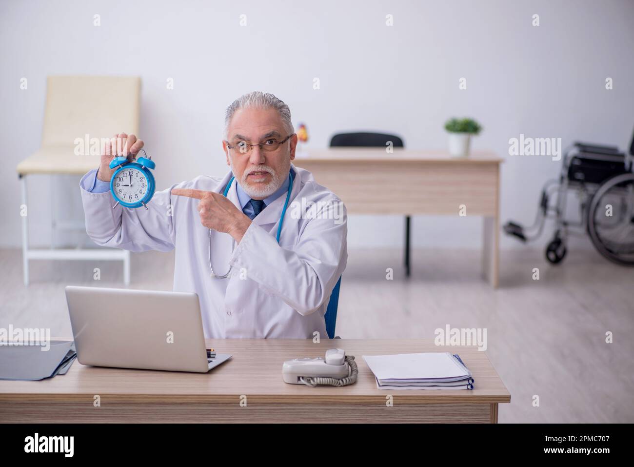 Old doctor in time management concept Stock Photo