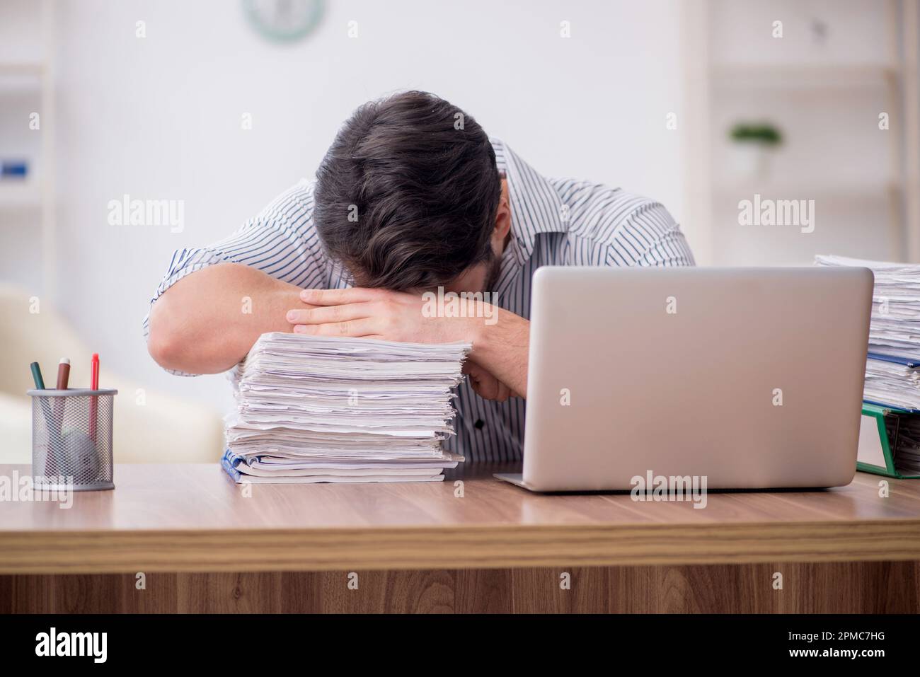 Young employee and too much work at workplace Stock Photo
