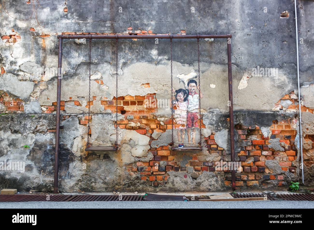 Street Art mural brother and sister on a swing kids on a wall in George Town on Penang island in Malaysia Stock Photo