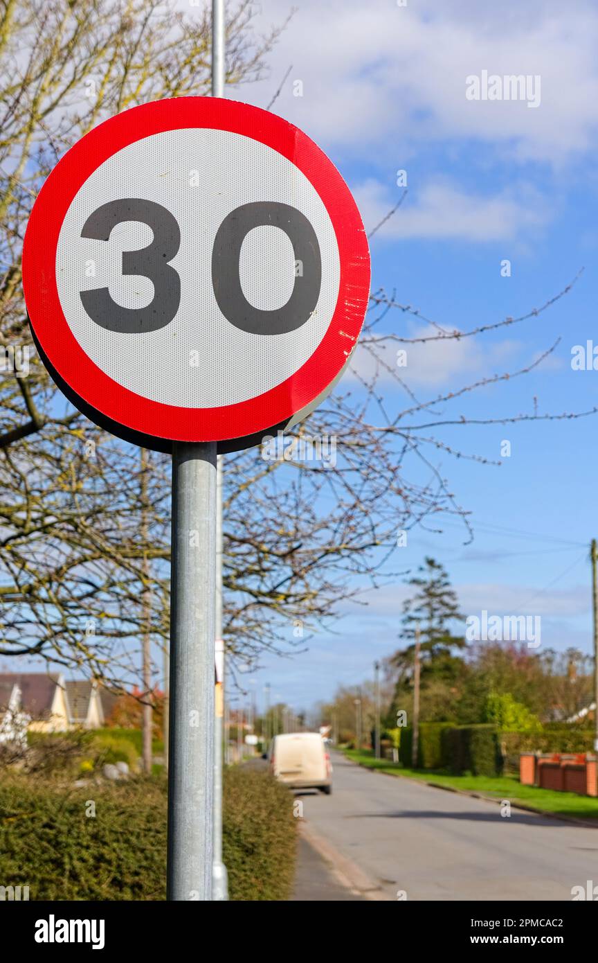 A British 30 mph speed limit sign with suburban road soft focused in the background Stock Photo