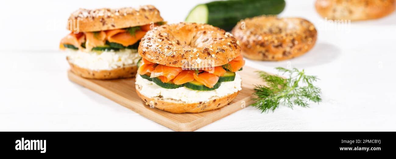 Bagel sandwich with salmon fish and cream cheese for breakfast on a kitchen board panorama Stock