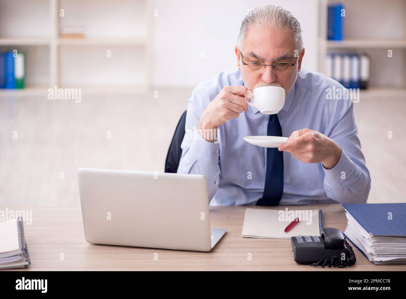Old employee drinking tea at workplace Stock Photo Alamy
