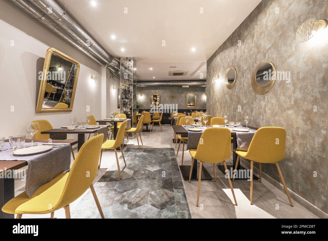 Dining room of a restaurant with assembled tables and chairs upholstered in yellow fabric Stock Photo