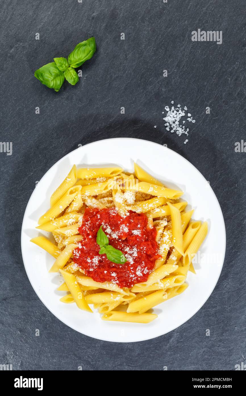 Penne Rigatoni Rigate pasta top view meal from Italy eat lunch with tomato sauce slate on a plate portrait format Stock Photo
