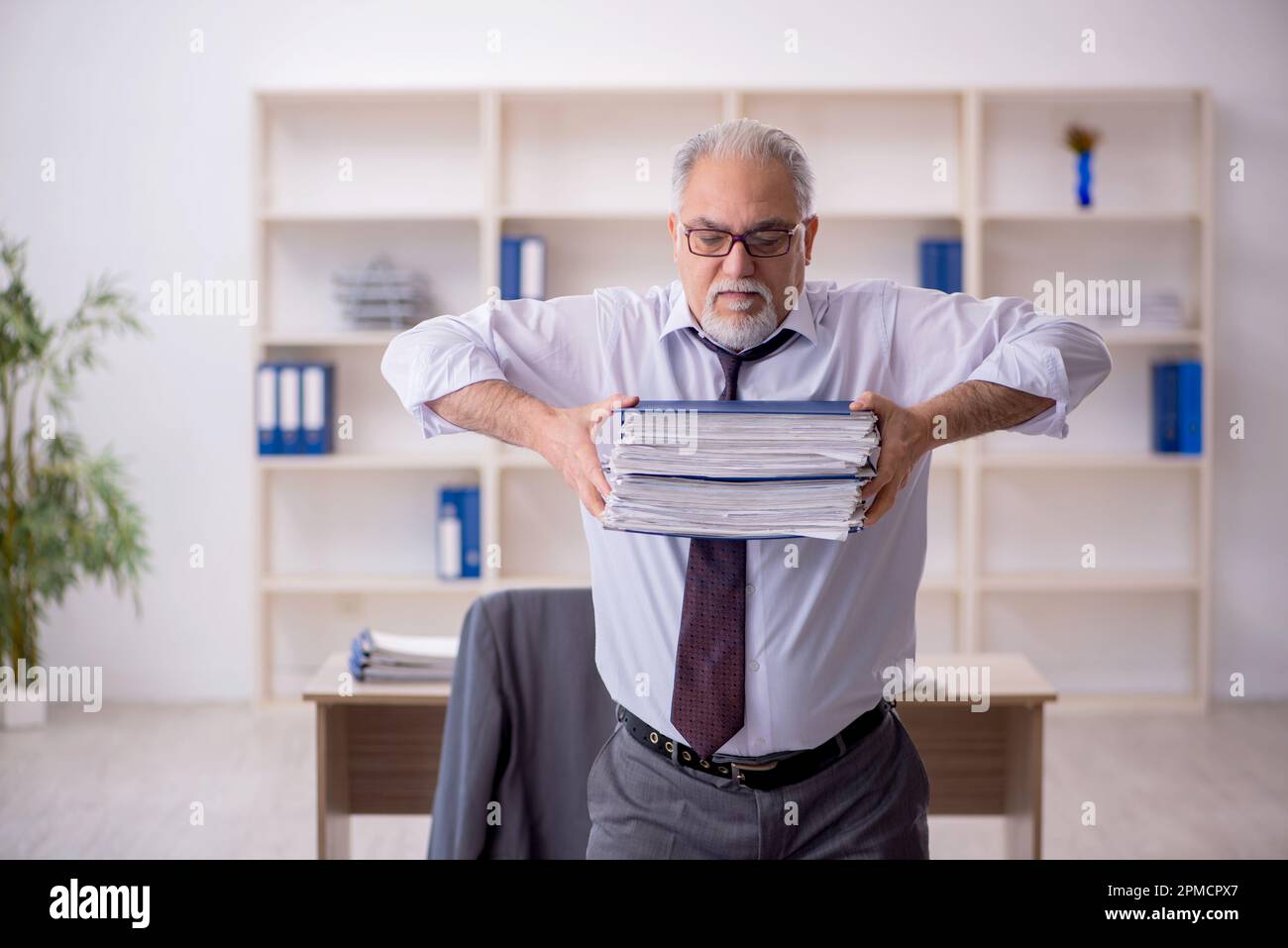 Old employee doing sport exercises during break Stock Photo