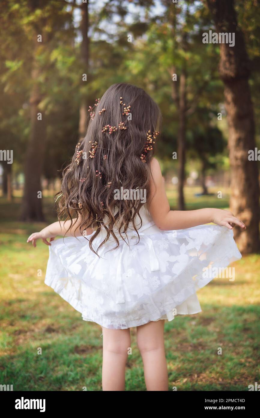 Little girl in a white dress is on her back playing in a fairy tale, copy space, children's day theme. Stock Photo