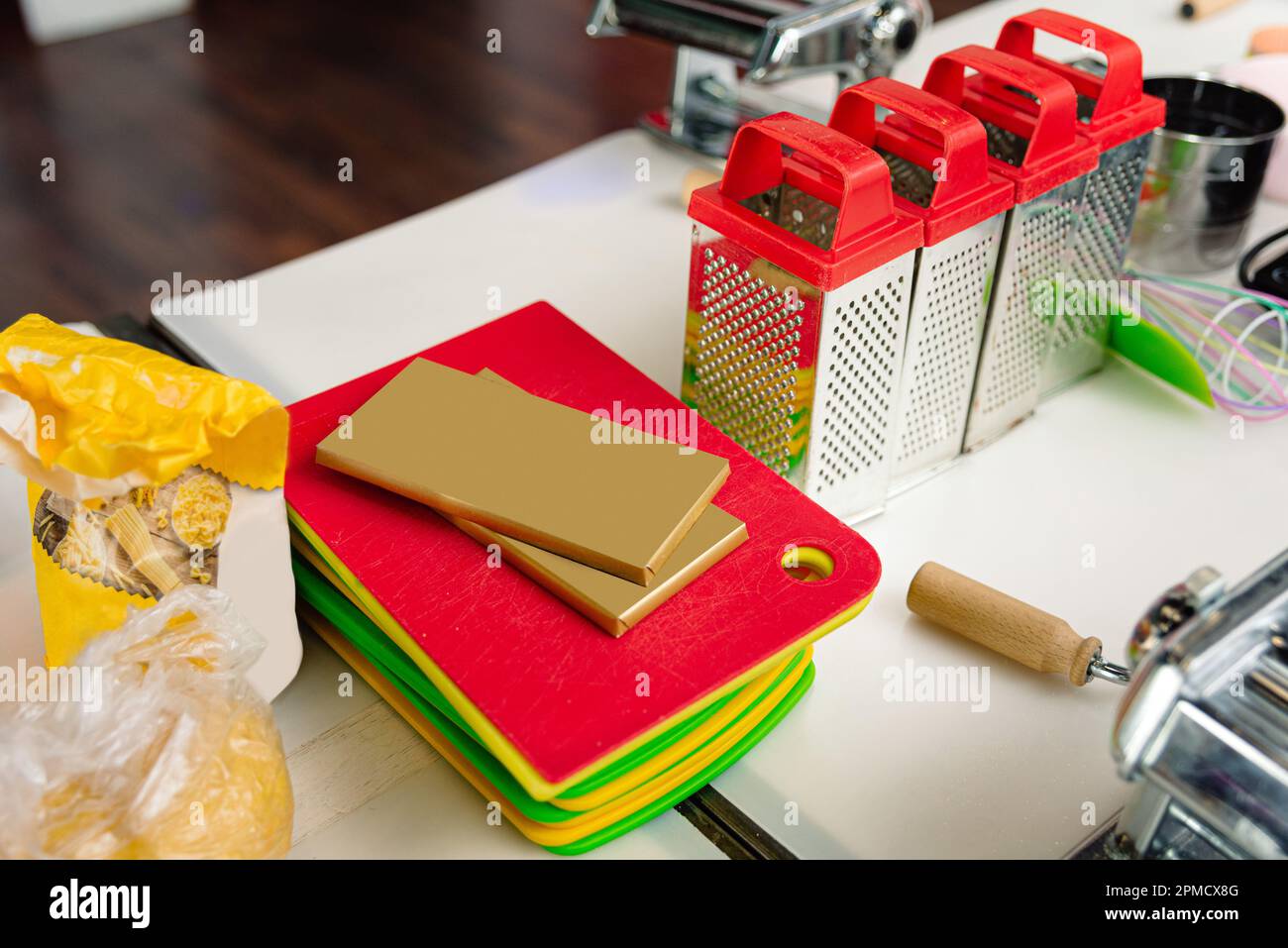 A stack of plastic slicing boards next to four hand-held steel grates and a packet of flour. Сooking kit at culinary master class. Stock Photo