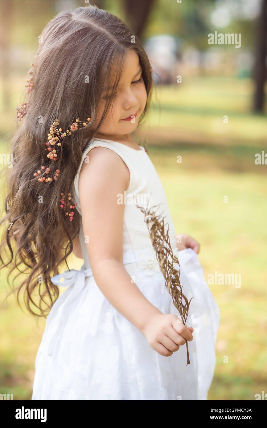Girl in white dress and princess crown plays in the forest as in a ...