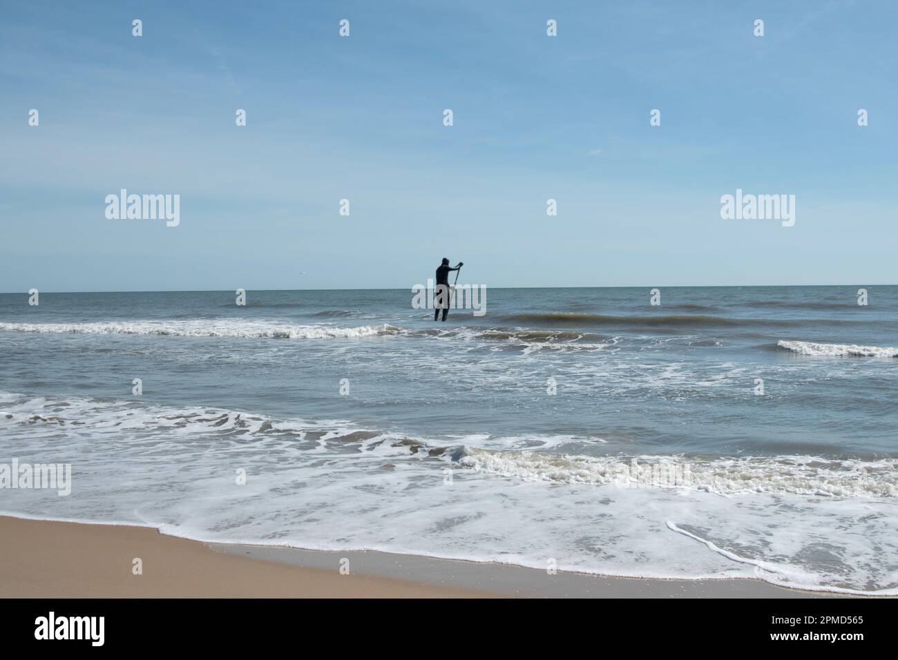 A person in a wetsuit, Standing up and paddle boarding in the Atlantic