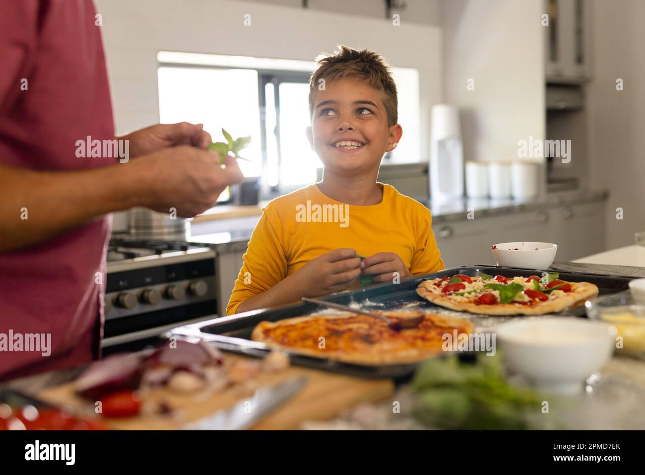 Midsection of caucasian grandfather with cute smilig grandson preparing pizza on kitchen island Stock Photo