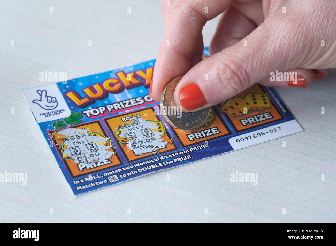 Woman scratching a Lucky Roll scratchcard with a british pound coin (£1) UK.  Scratchcards, scratch card, scratch cards Stock Photo