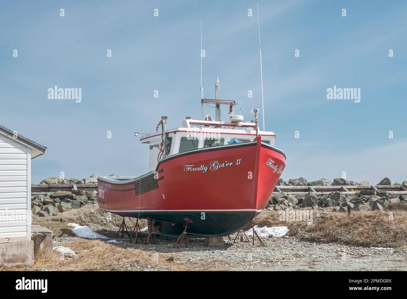 Red fishing boat sits on shore for the winter awaiting the upcoming