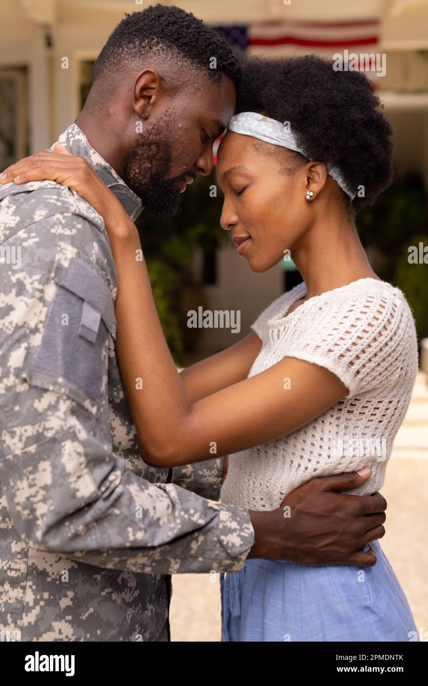 Loving african american army soldier husband and wife with head to head standing outside house Stock Photo