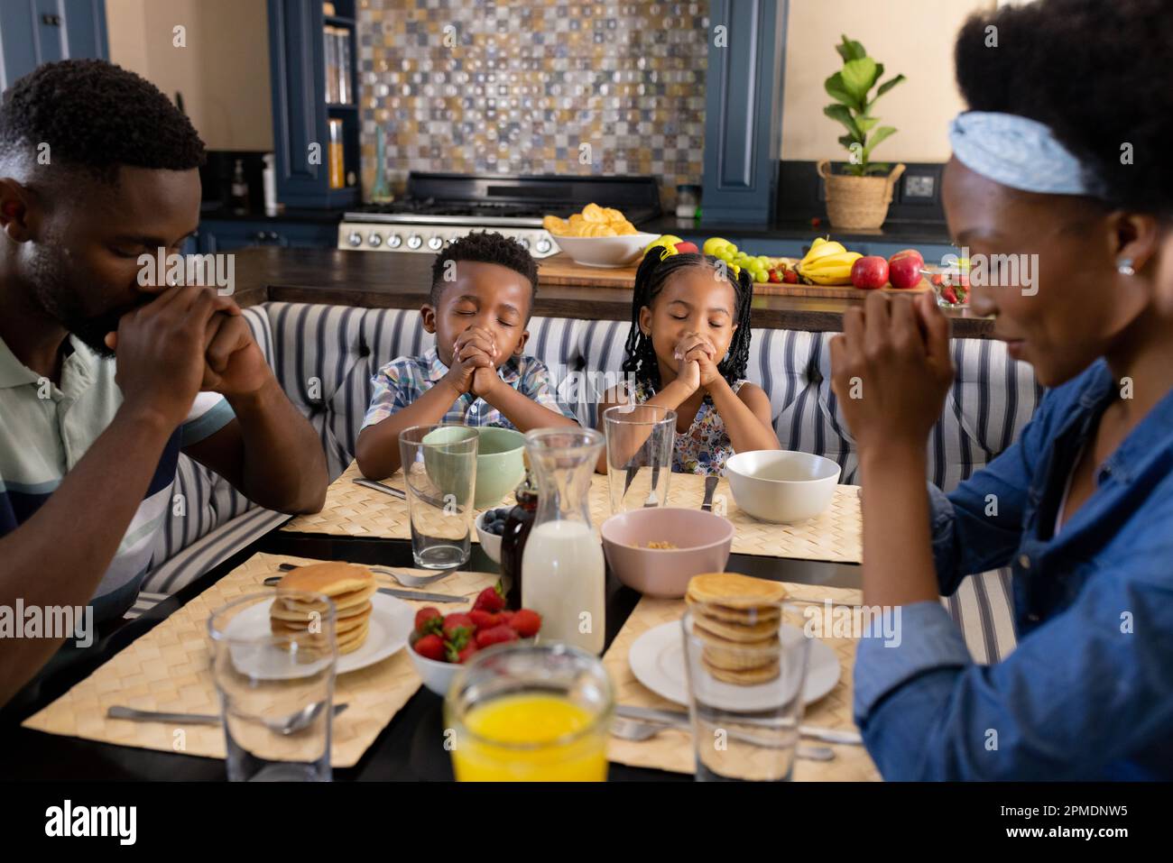 African american parents and children saying grace at dining table before breakfast in morning Stock Photo
