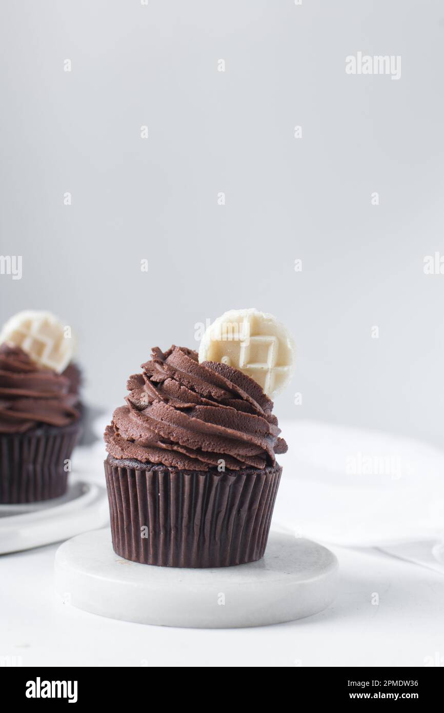 Chocolate cupcake with dark chocolate buttercream, double chocolate cupcakes with american buttercream, tall swirl frosting on a cupcake with a wafer Stock Photo