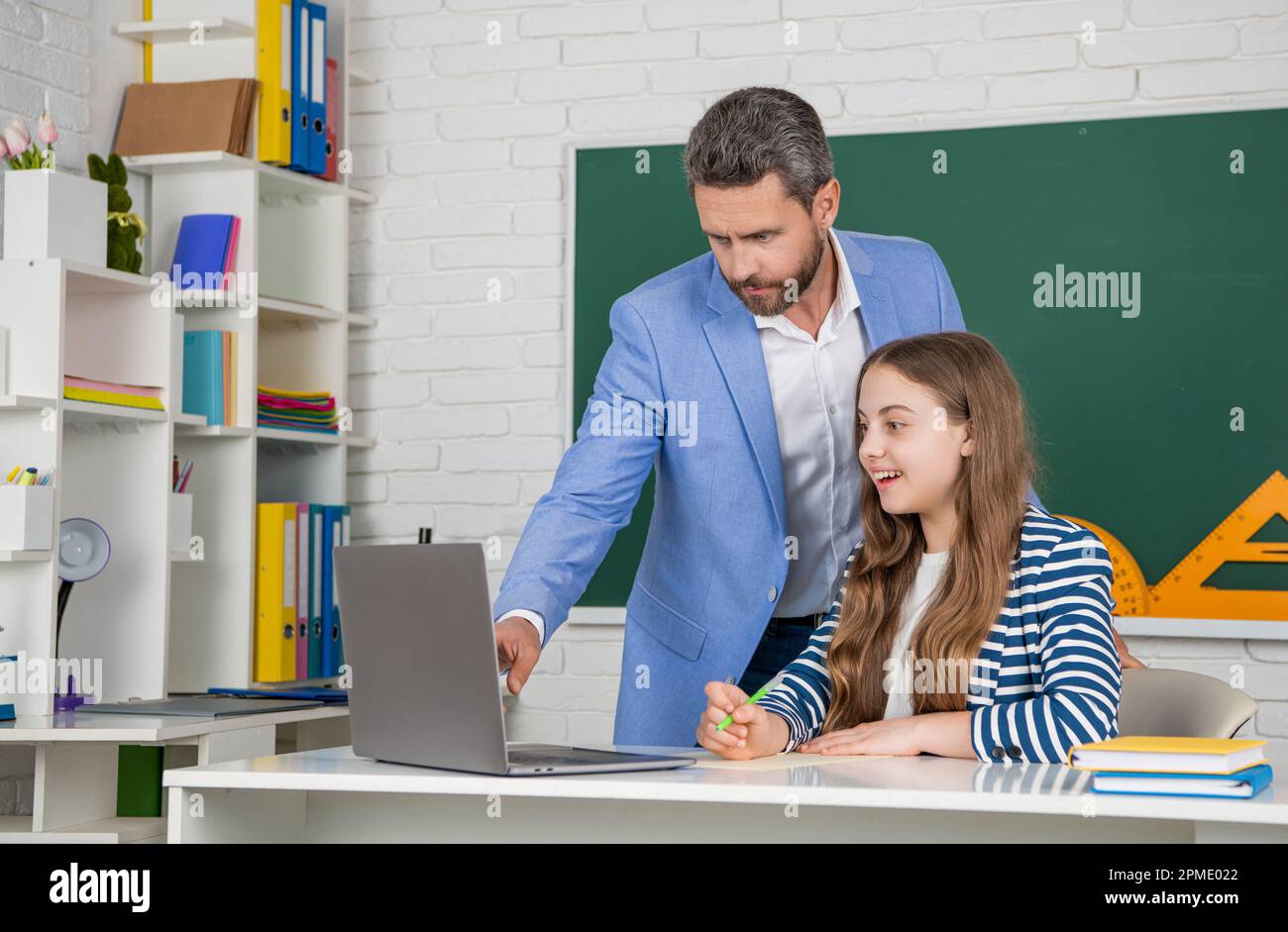 cheerful child with teacher in classroom use laptop Stock Photo - Alamy