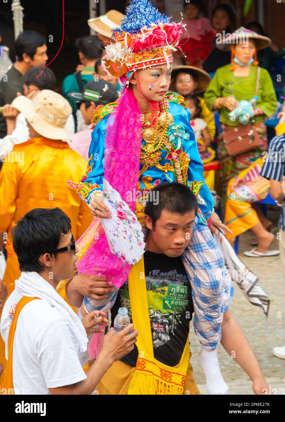 Pai,Mae Hong Son,Thailand-April 4th 2023:Boys,aged between seven and fourteen years,about to be ordained as Buddhist monks,are carried on men's should Stock Photo