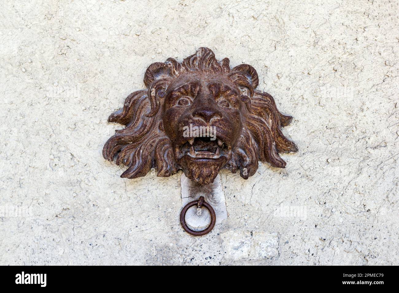 Rusty lion head with iron ring that was used to tie horses on wall Stock Photo