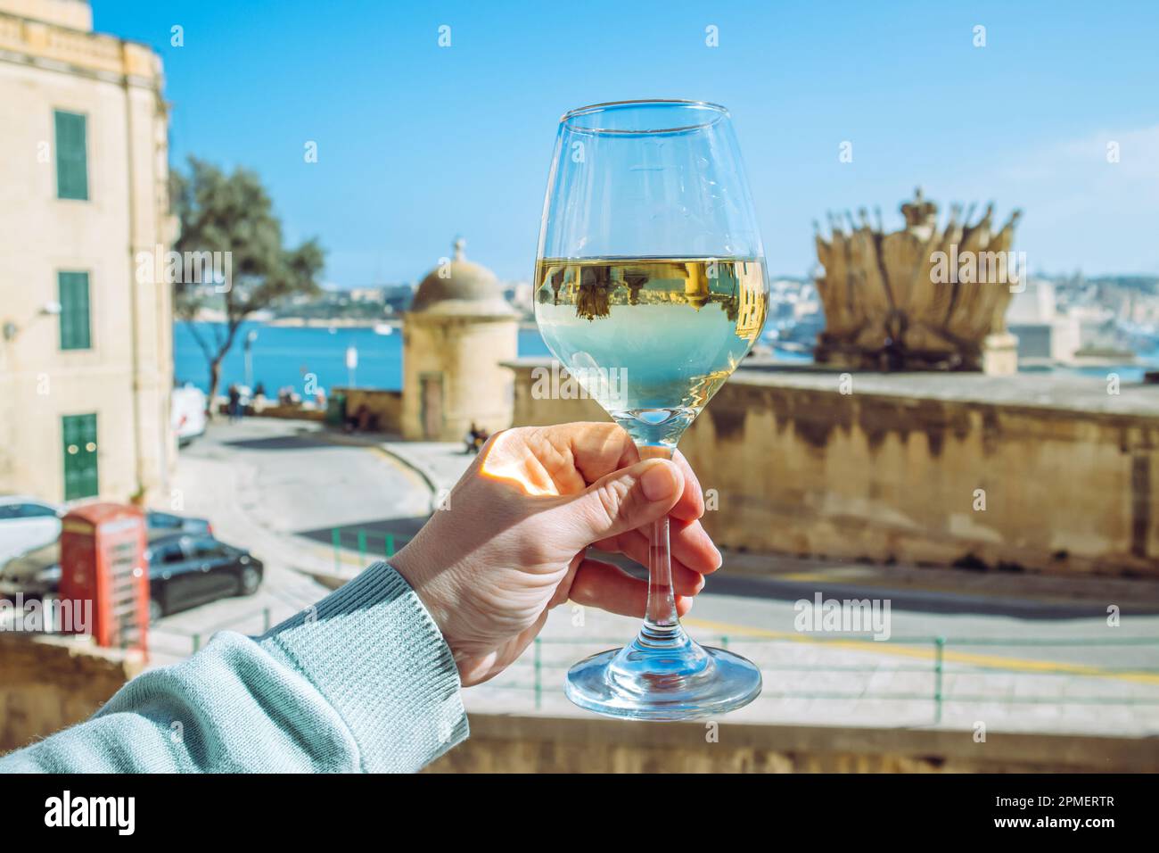 Selective focus on woman hand holding glass of white wine in beautiful