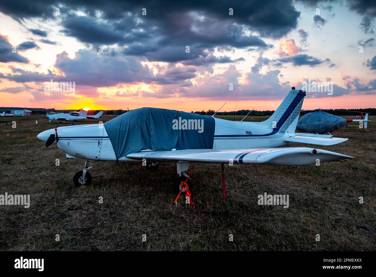 Covered airplanes and helicopters of small aviation at the airfield at