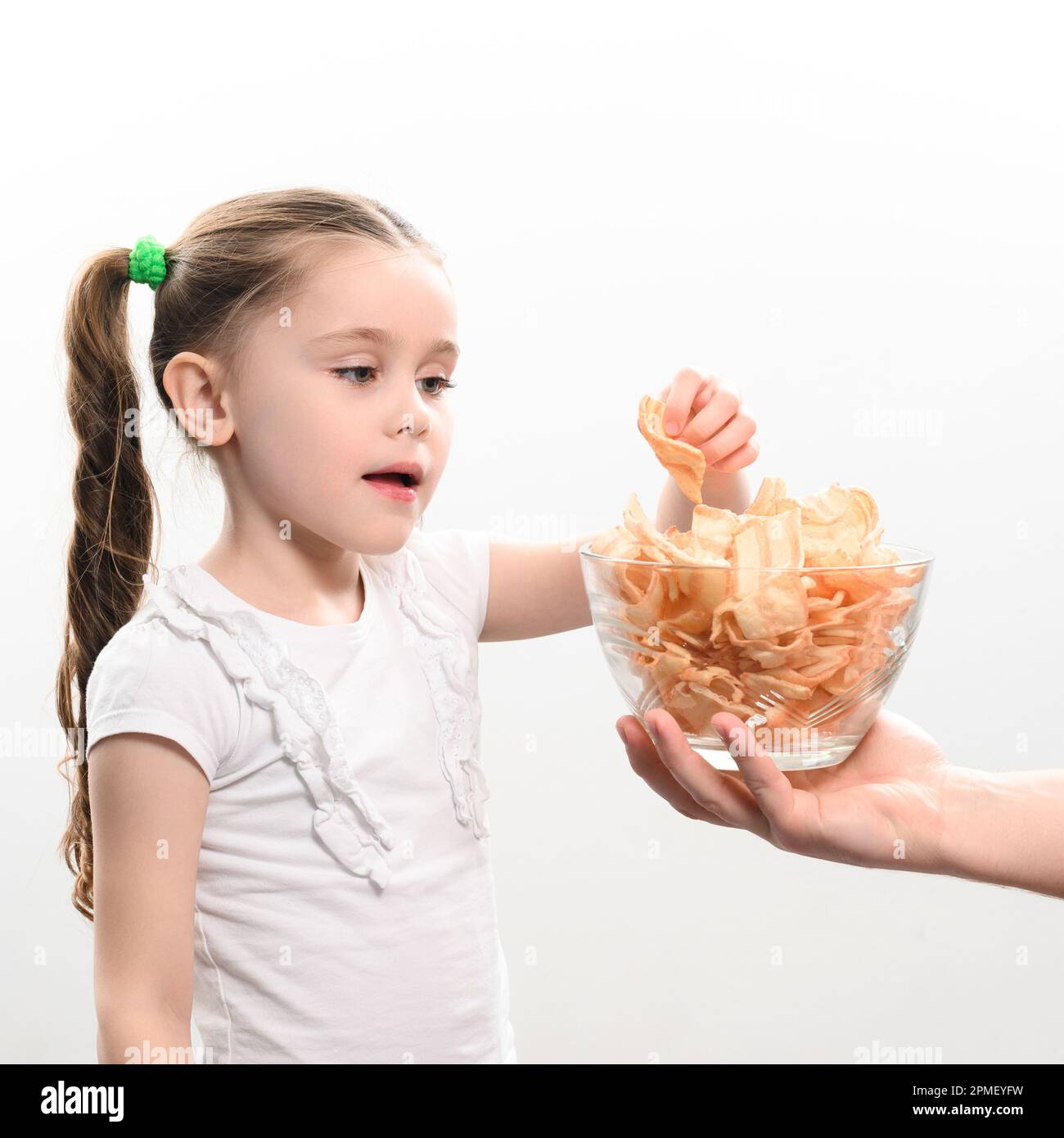 Little girl is given a big bowl of chips snacks with lard, white