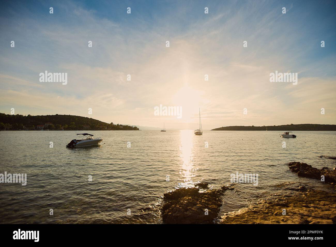 Small sailboats on the background of the setting sun in the town of Loviste on the Peljesac peninsula. Stock Photo