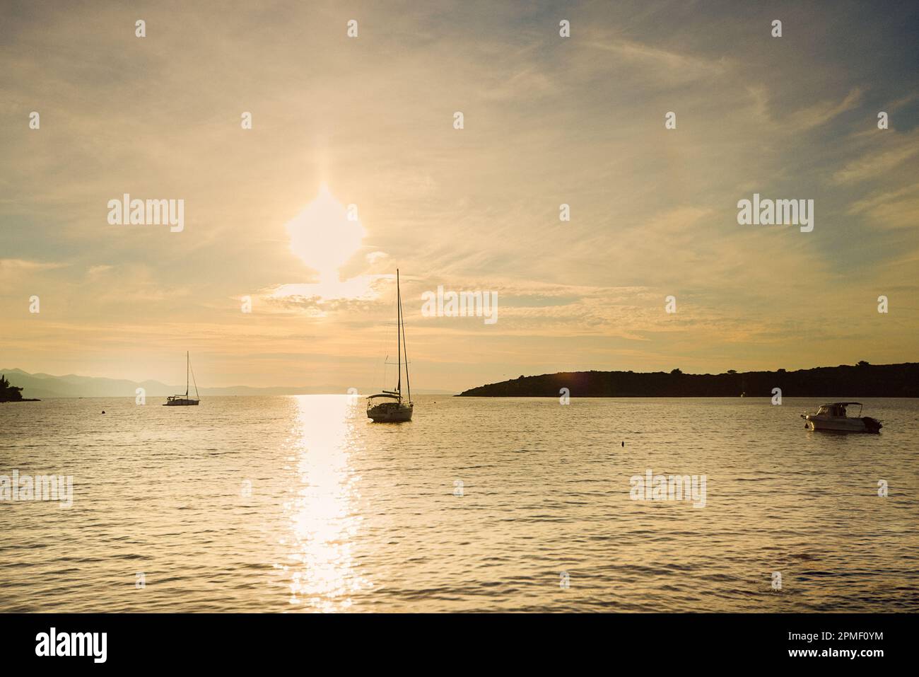 Small sailboats on the background of the setting sun in the town of Loviste on the Peljesac peninsula. Stock Photo
