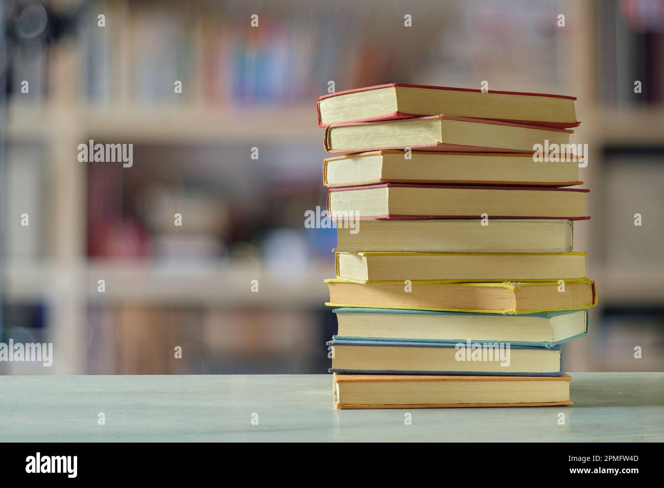 Stack of books with blurred bookshelf background, reading, learning
