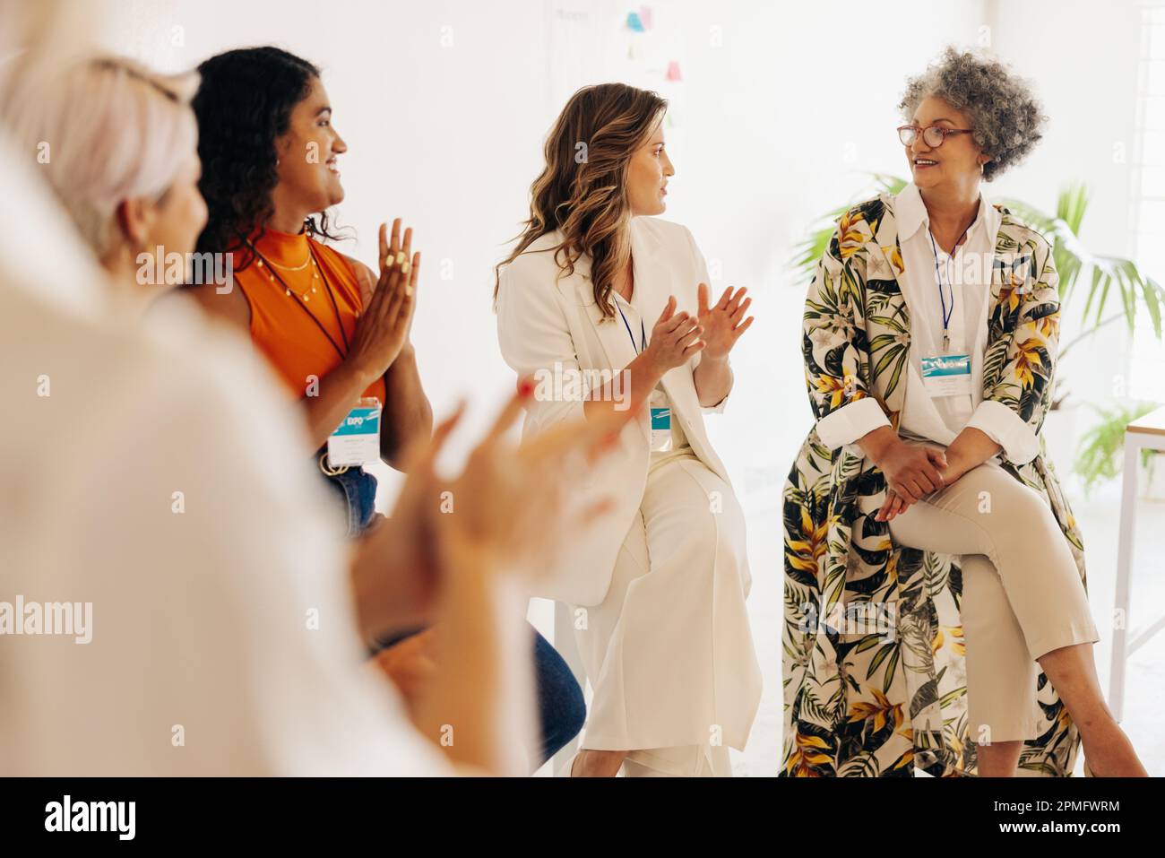 Cheerful businesswomen applauding their colleague during a conference meeting. Group of multicultural businesswomen working together in an all-female Stock Photo