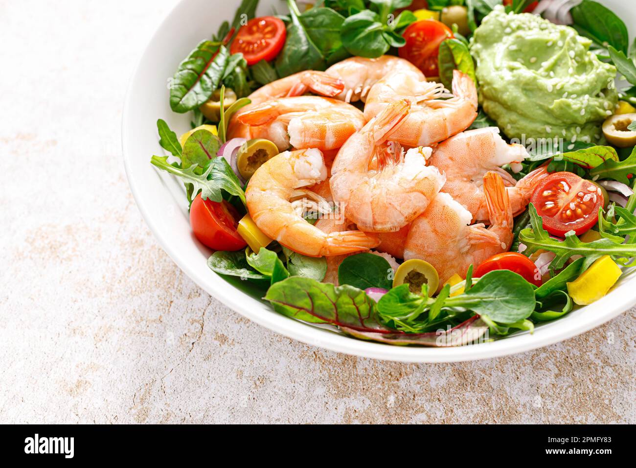 Shrimp and leafy vegetables salad with tomato, bell pepper, olive and avocado sauce Stock Photo