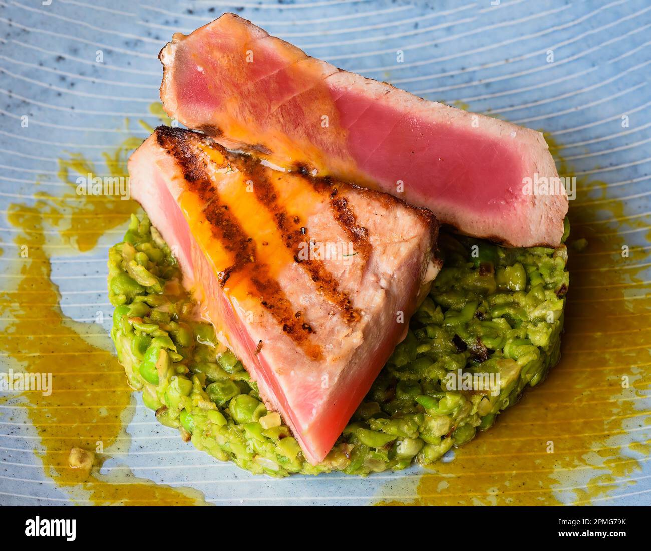 Tuna steak medium rare served with peas isolated on black background