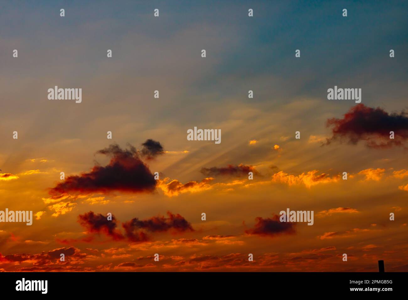 Sun rays through the clouds at sunset. Partly cloudy sky. Dramatic cloudscape. Stock Photo