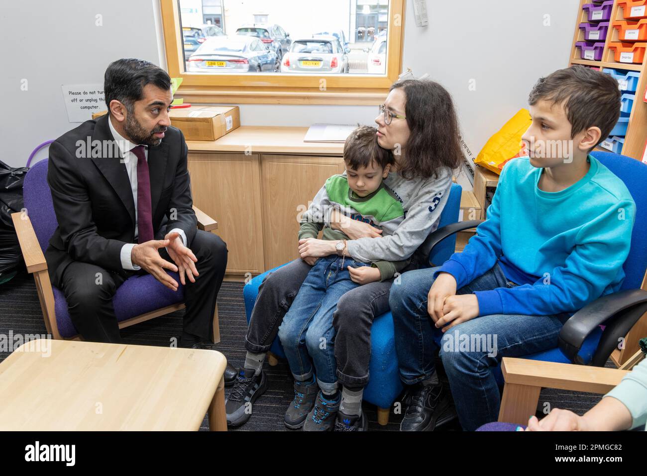 First Minister Humza Yousaf speaks to Ukrainian refugees, Maryna Chyshkala, and her children Misha, 5, and Lev, 12, during a visit to a nursery at Crookston Castle Primary School, Glasgow, to see how a project to integrate child poverty interventions and bring services together across the city is having a positive impact for families. Picture date: Thursday April 13, 2023. Stock Photo