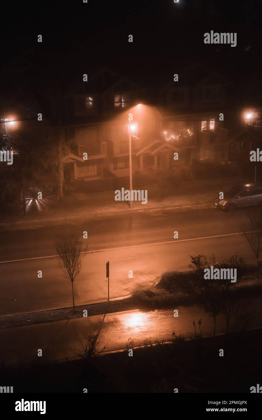 A dramatic streetlight shines down a wet and glistening street in