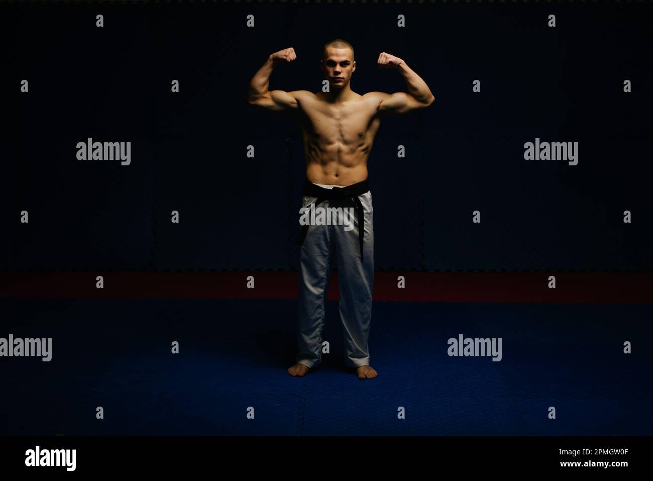 Good looking teen boy posing with his muscles at the karate studio