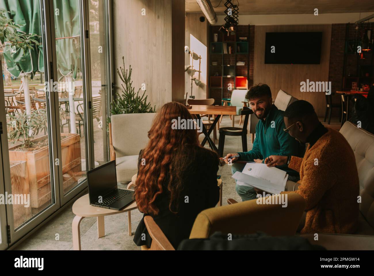 Three overjoyed multiracial business people working together on a new project and having fun conversation Stock Photo