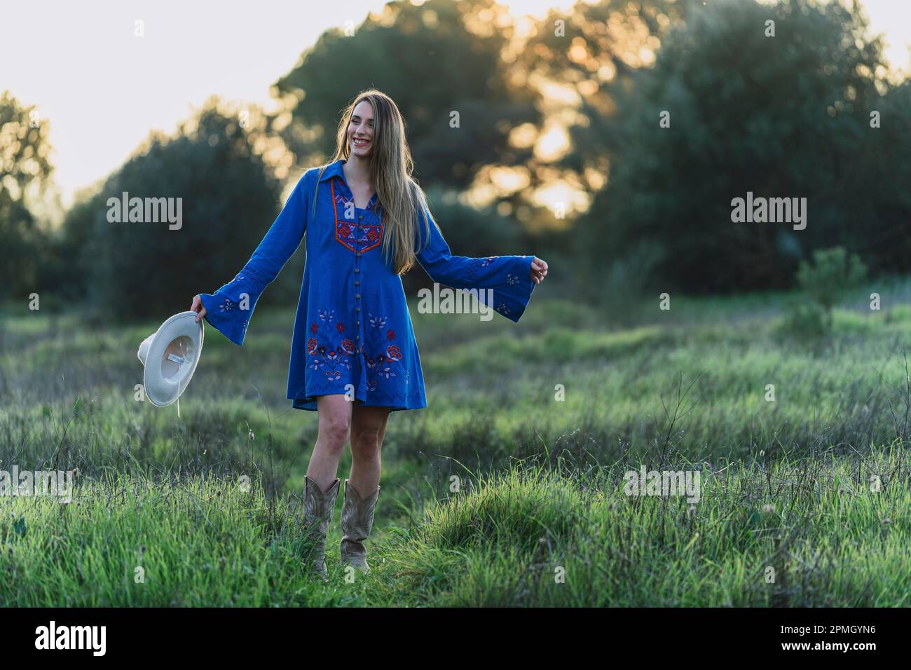 A young smiling woman in a blue dress walking in the green field Stock ...