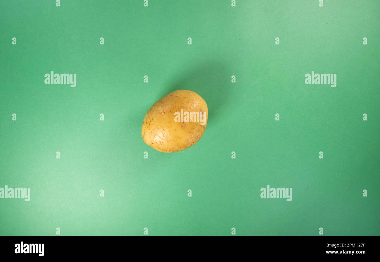 single small potato isolated on a dark green background Stock Photo