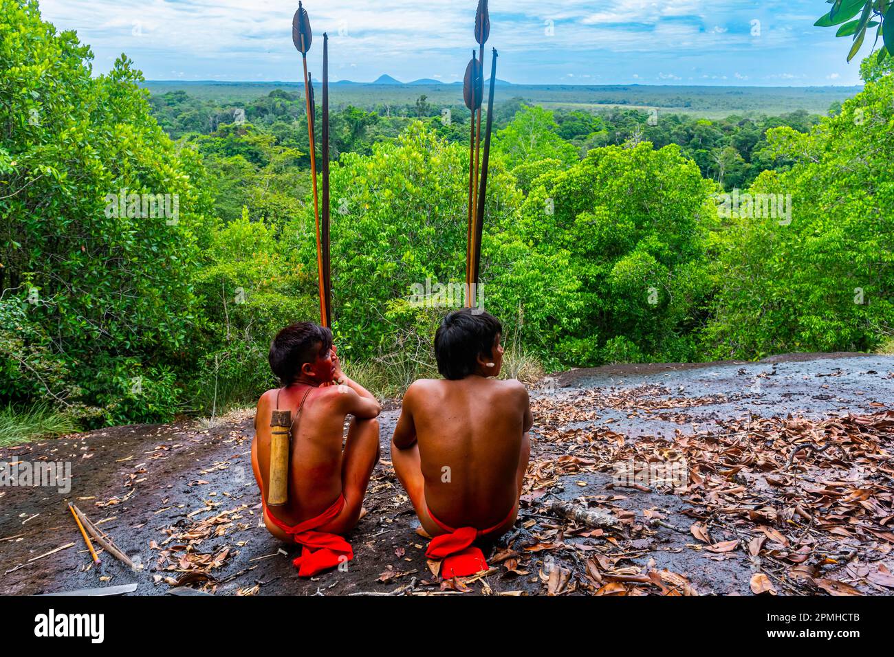 Yanomami tribesmen sitting on a giant rock in the jungle, southern Venezuela, South America Stock Photo