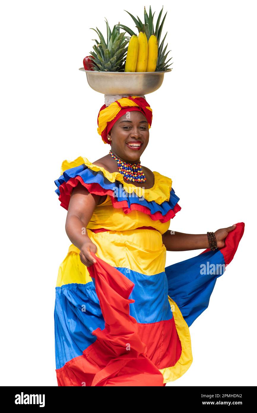 Happy fresh fruit street vendor, Palenquera, dancing on white background. Cheerful Afro-Colombian woman in traditional costumes, Cartagena, Colombia. Stock Photo