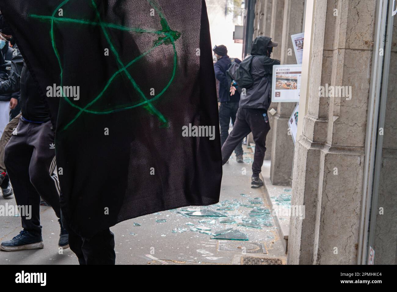 France, Lyon, 2023-04-06. Thugs destroying a window during a demonstration against pension reform and a black flag with an A on it. Stock Photo