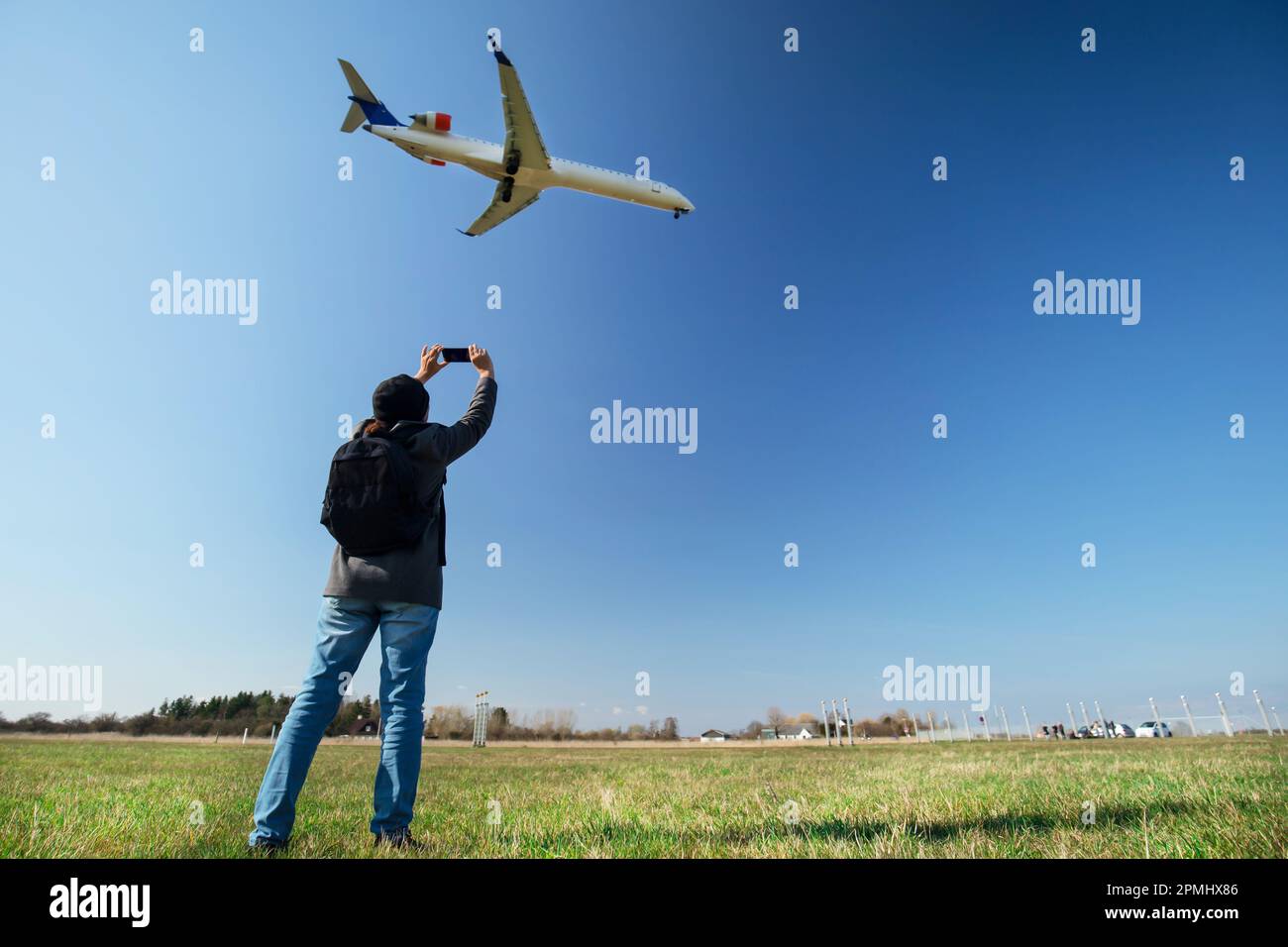 Girl taking photo of an aircraft landing at Copenhagen Airport Stock Photo