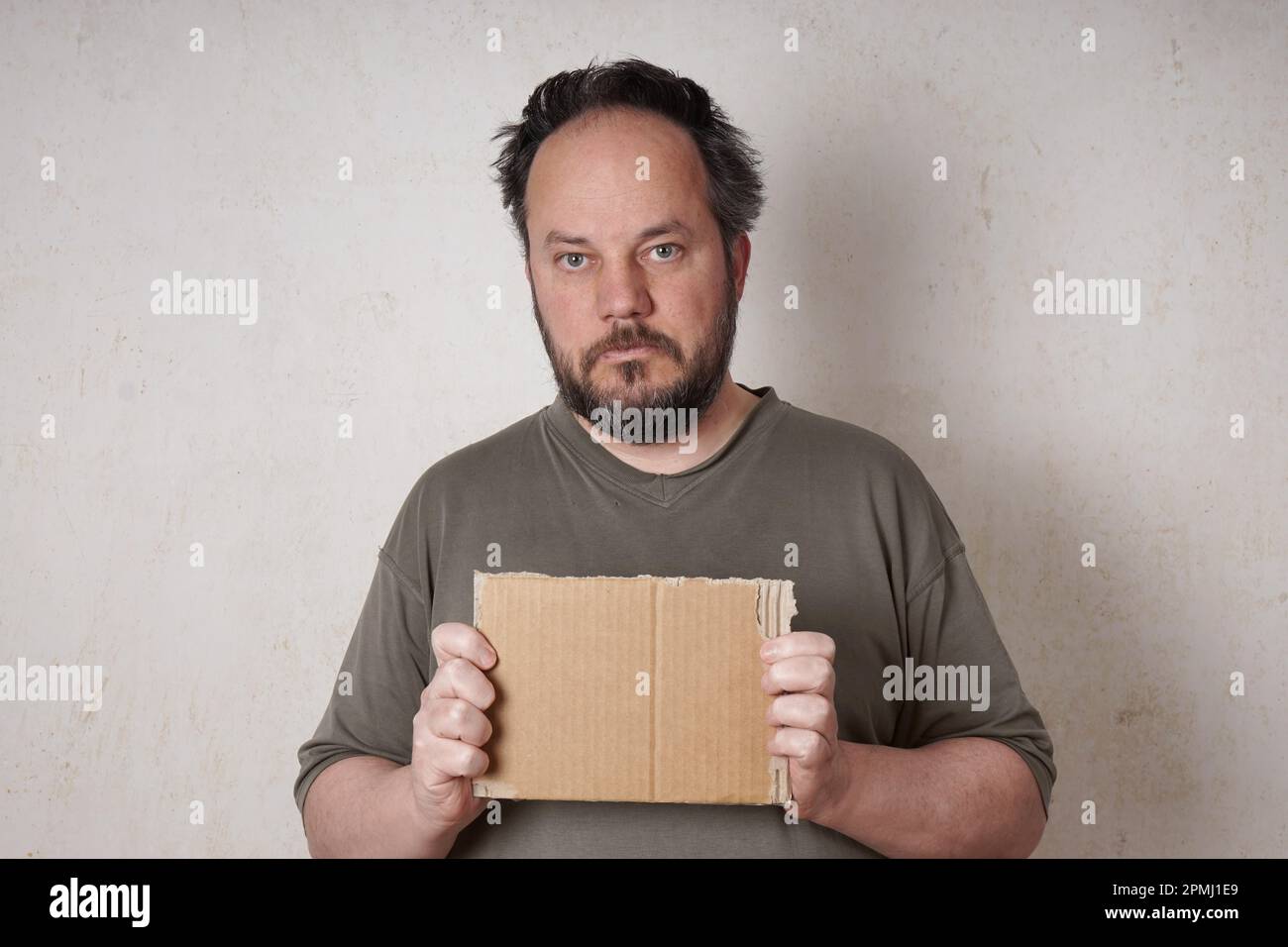 grubby scruffy man holding blank cardboard sign Stock Photo